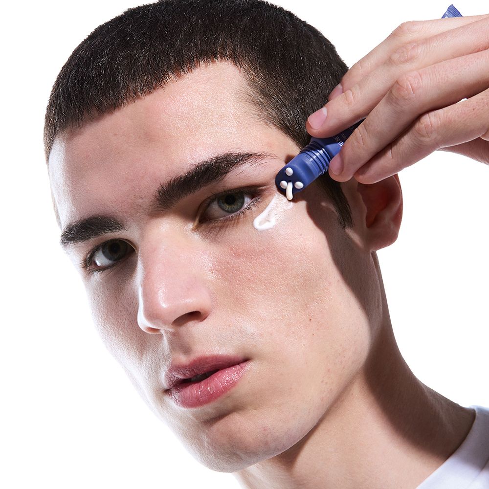 Uomo applica crema. Tubo blu con applicatore roll-on. Marchio Face D.