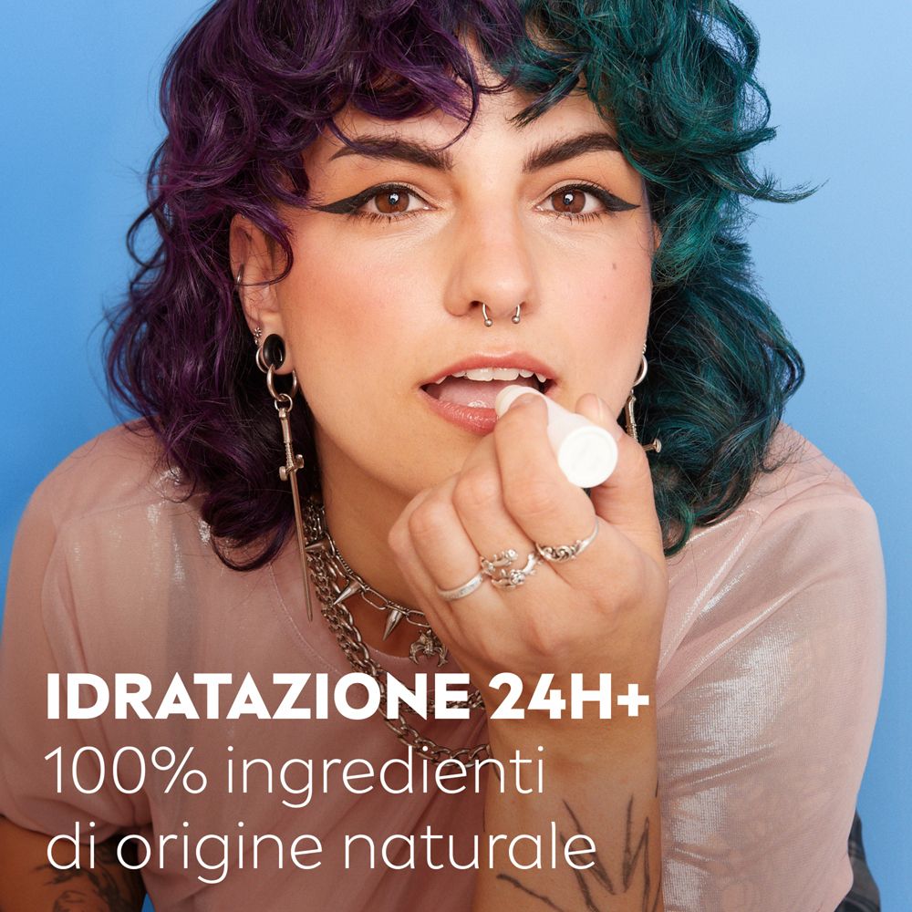 Persona usa stick labbra Labello. Stick in astuccio bianco. Scritta: IDRATAZIONE 24H+ 100% ingredienti di origine naturale.