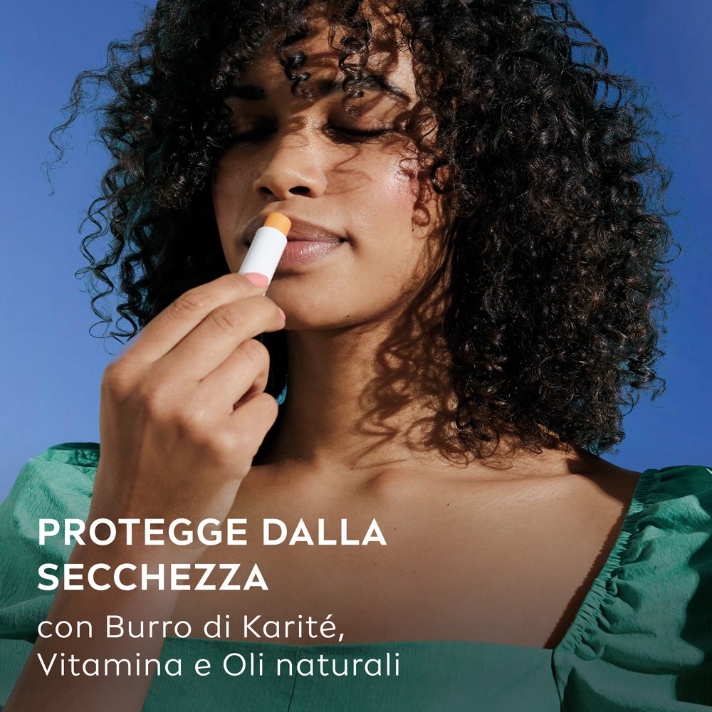 Donna usa Labello Mango Shine. Protegge dalla secchezza. Con burro di karité, vitamine e oli naturali.