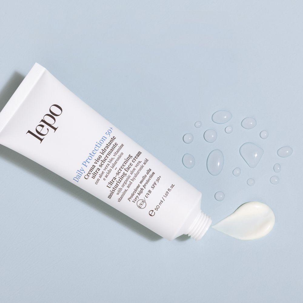 Tubo bianco con prodotto. La crema viene spremuta dal tubo. Testo: Daily Protection 50+, crema viso ultra schermante. Marchio: lepo.