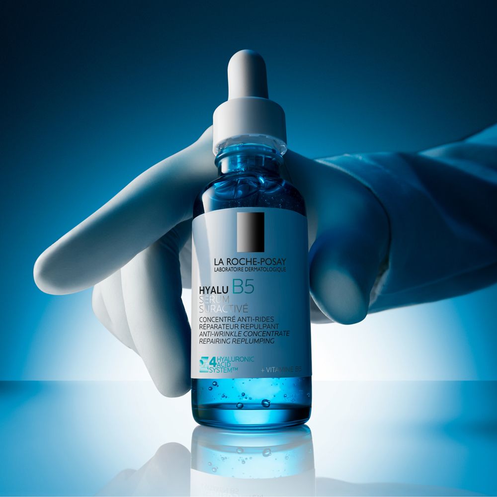 Flacone di siero blu con contagocce, tenuto da una mano con guanto bianco. Marchio: La Roche-Posay.