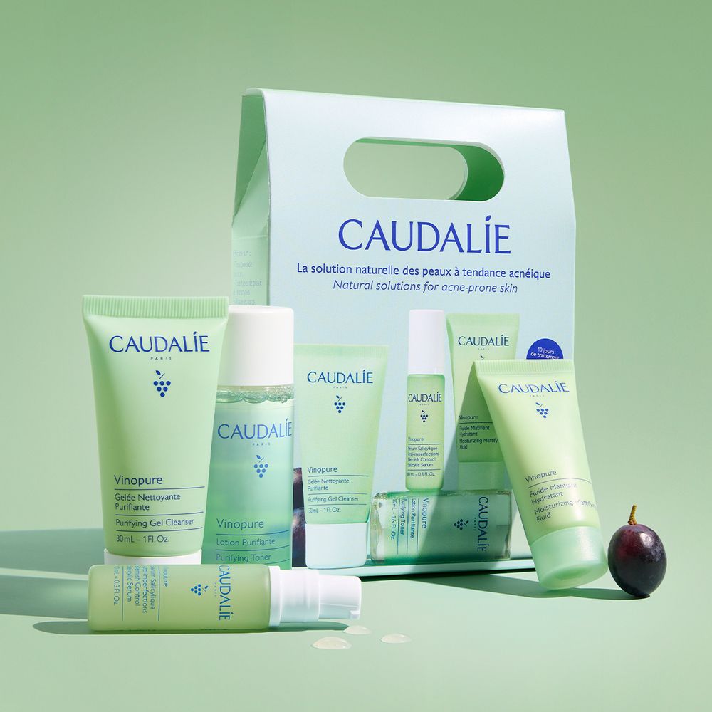 Set Caudalie con gel detergente, lozione, siero e idratante. Confezione verde con logo e testo. Uva nera.