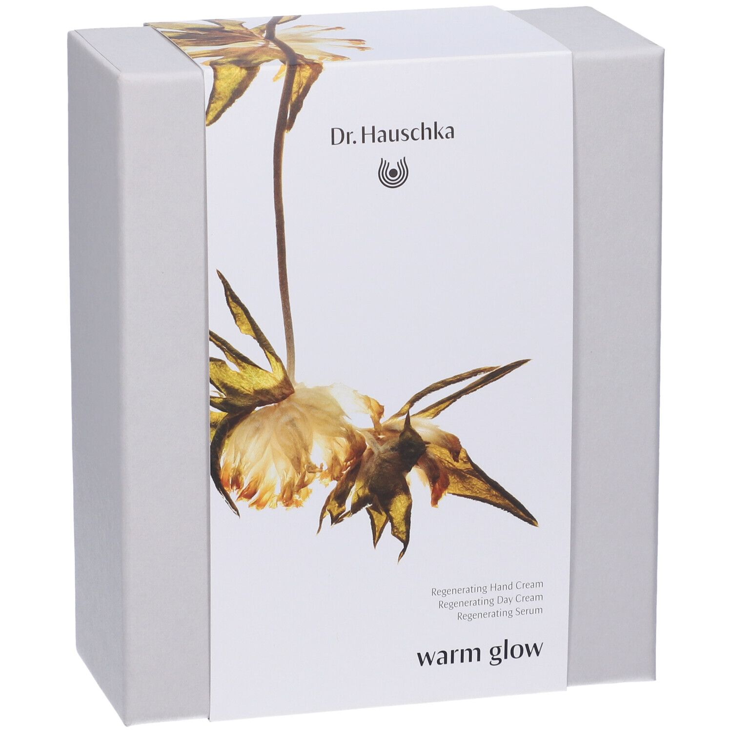 Confezione regalo con design floreale. Scritta: Dr. Hauschka, warm glow. Contiene crema mani, crema giorno, siero.