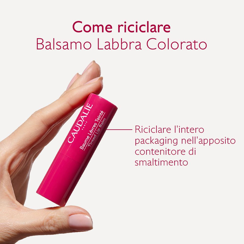 Mano che tiene il balsamo labbra. Prodotto e logo Caudalie visibili.