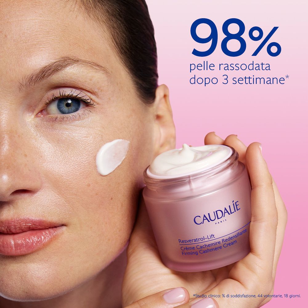 Donna con crema sulla guancia. Vasetto di crema Caudalie. Testo: Resveratrol-Lift.