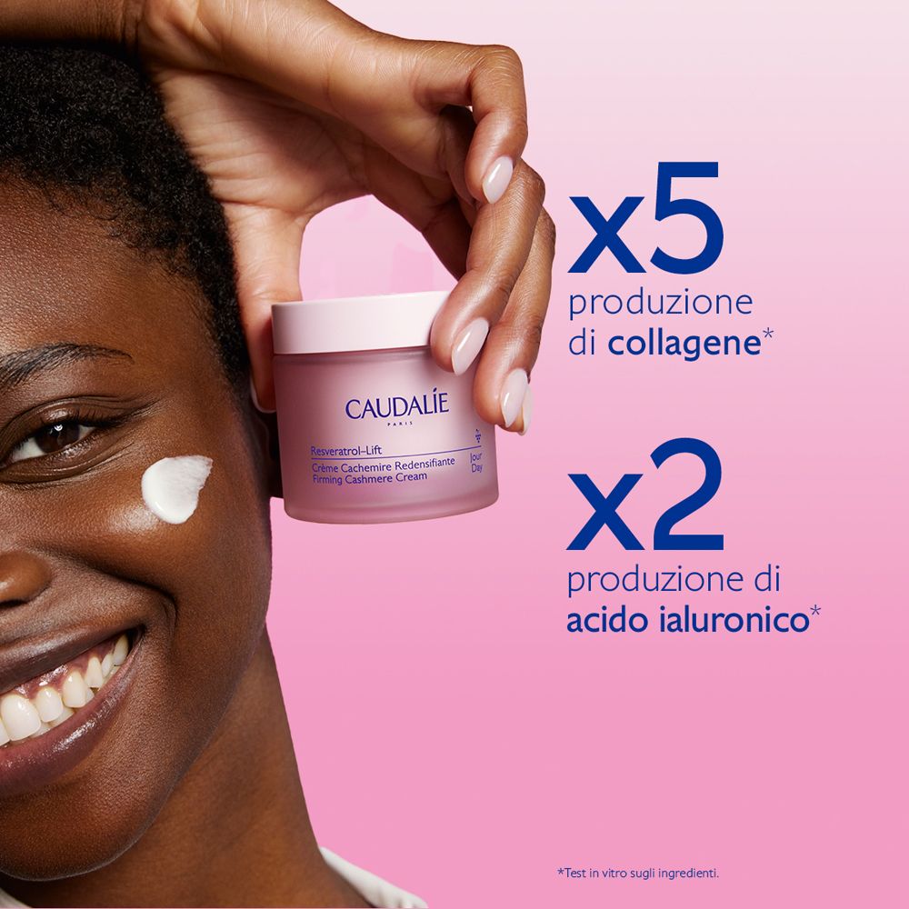 Donna di colore con crema sulla guancia. Vasetto di crema Caudalie. Testo: Resveratrol-Lift.