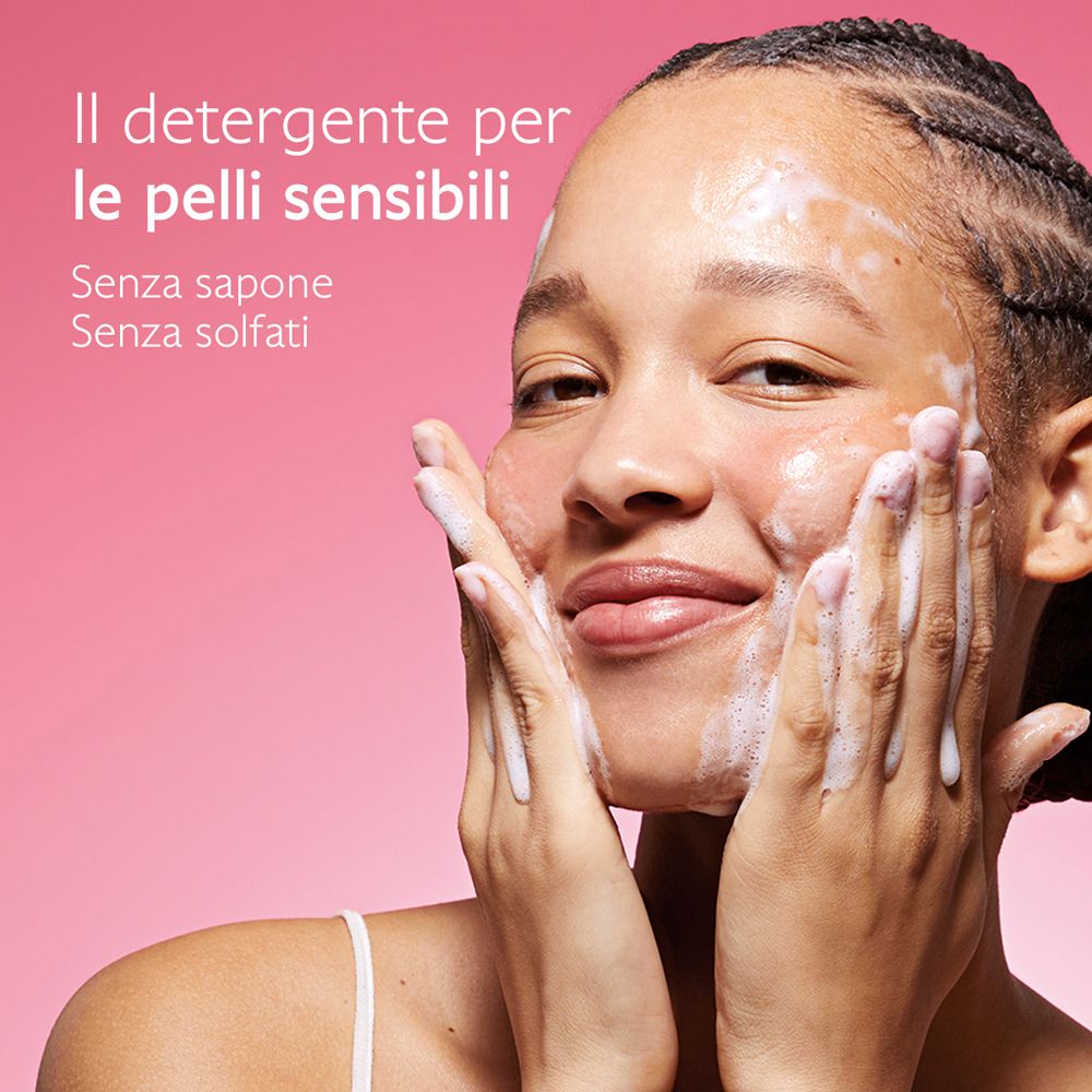 Donna si lava il viso con schiuma. Testo: Il detergente per le pelli sensibili. Senza sapone. Senza solfati.