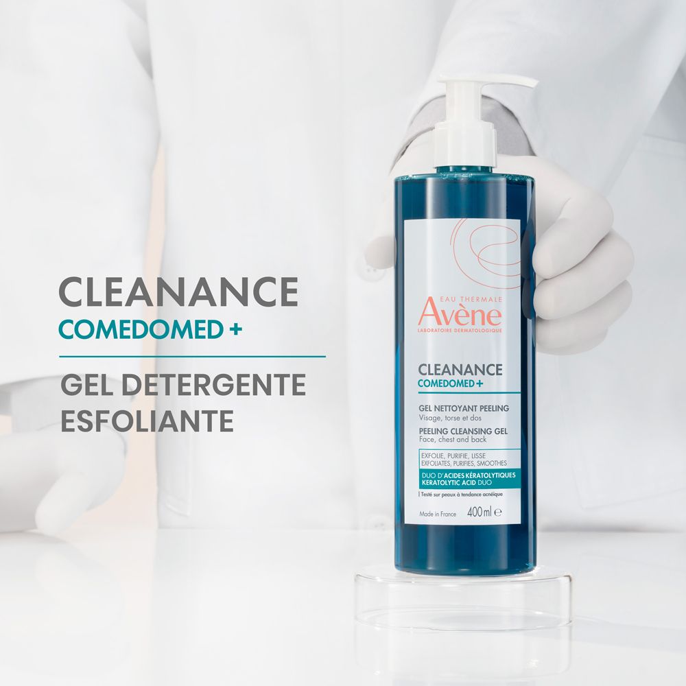 Gel blu in flacone con dosatore. Scritta: Cleanance Comedomed+. Gel Detergente Esfoliante. Mani con guanti lo tengono.