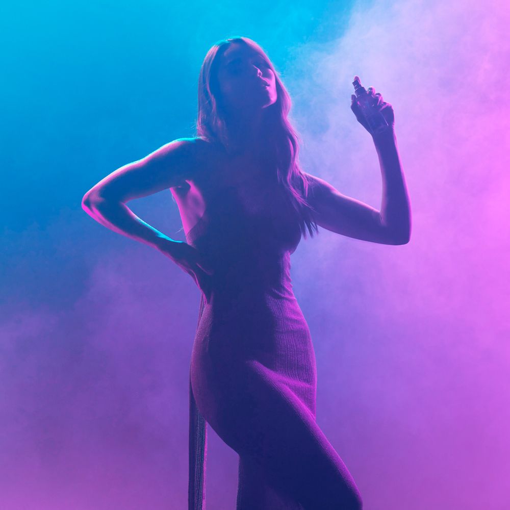 Silhouette di una donna che tiene un flacone spray. Sfondo: blu e rosa. Nebbia.
