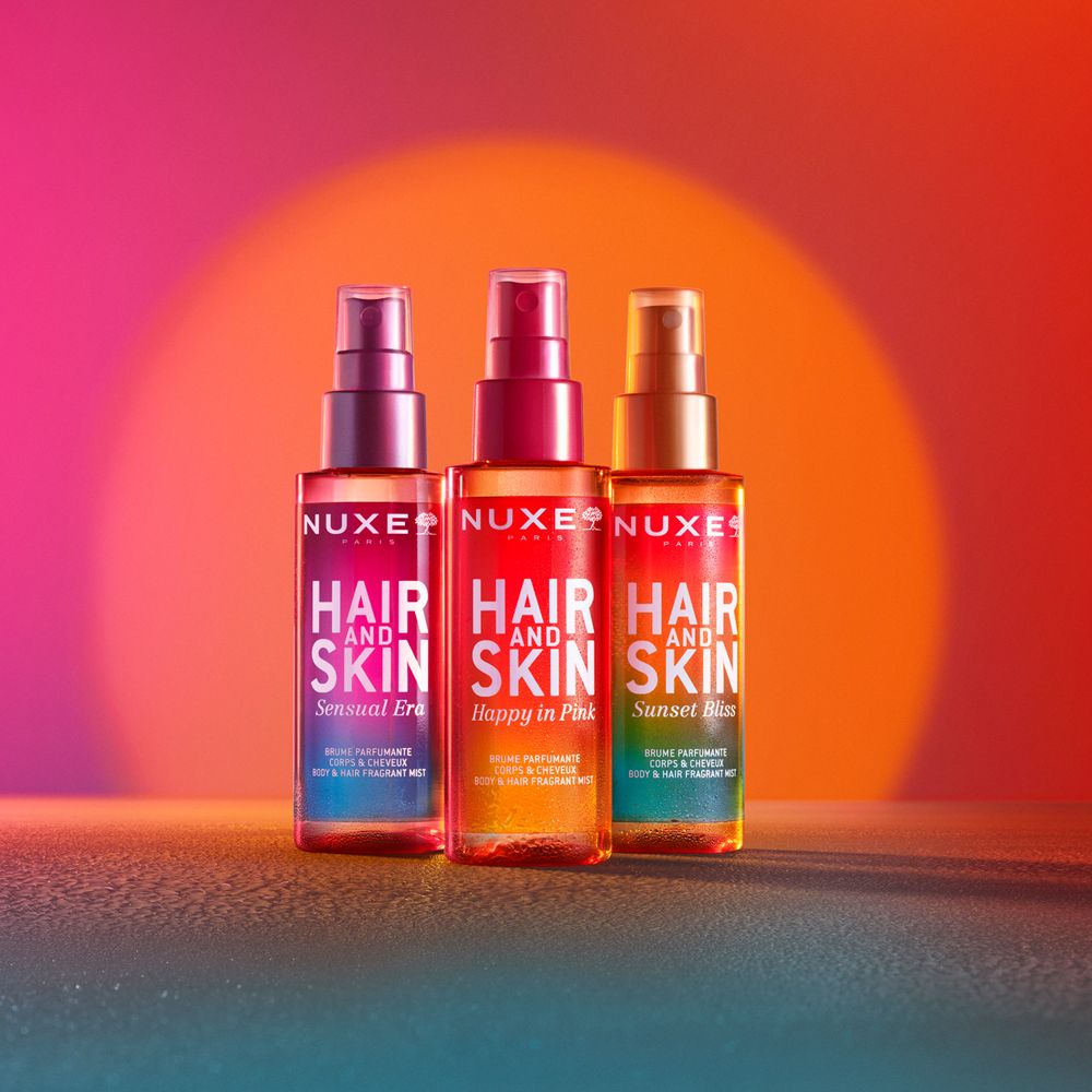 Tre spray Nuxe Hair and Skin. Sensual Era, Happy in Pink, Sunset Bliss. Sfondo sfumato.