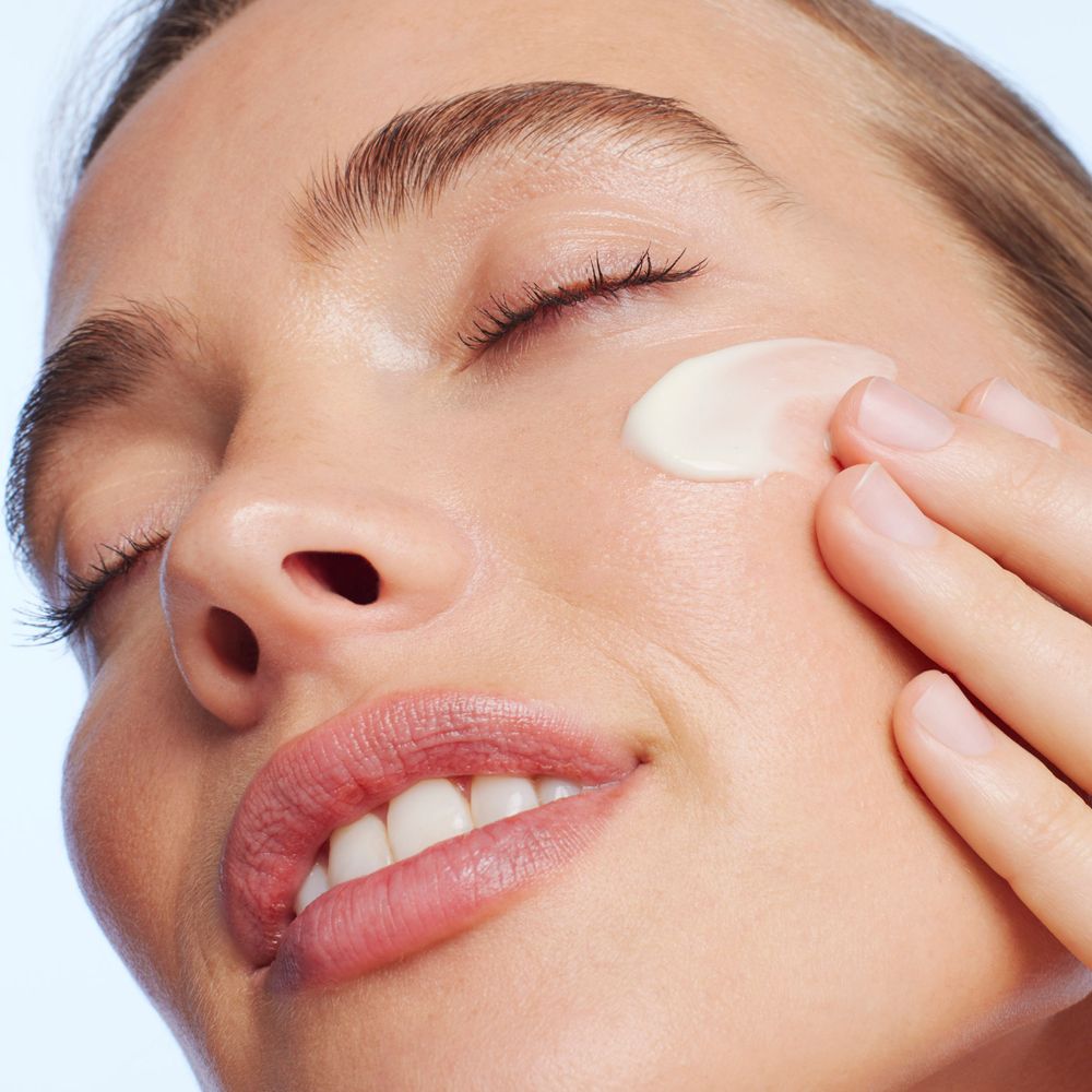 Donna che applica la crema. Viso, occhi chiusi. Crema sulla pelle.