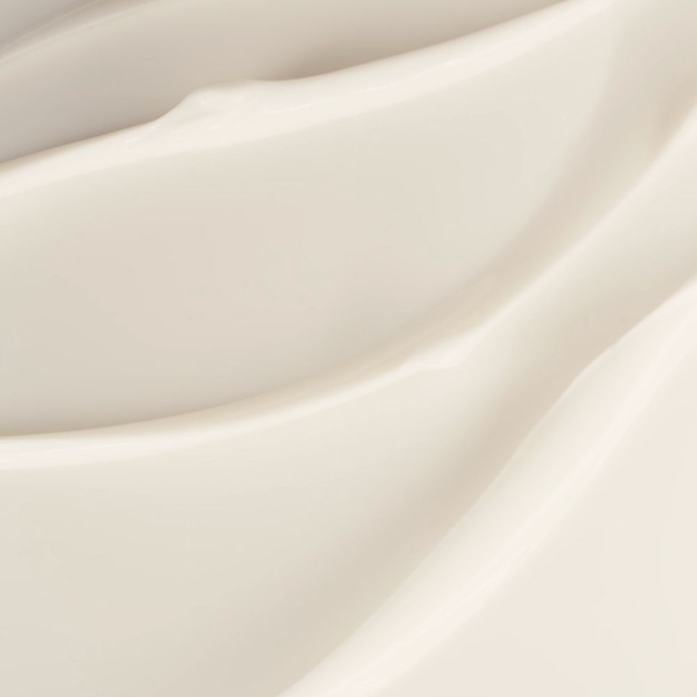 Primo piano di crema color crema. Texture liscia e ondulata. Nessun altro dettaglio visibile.
