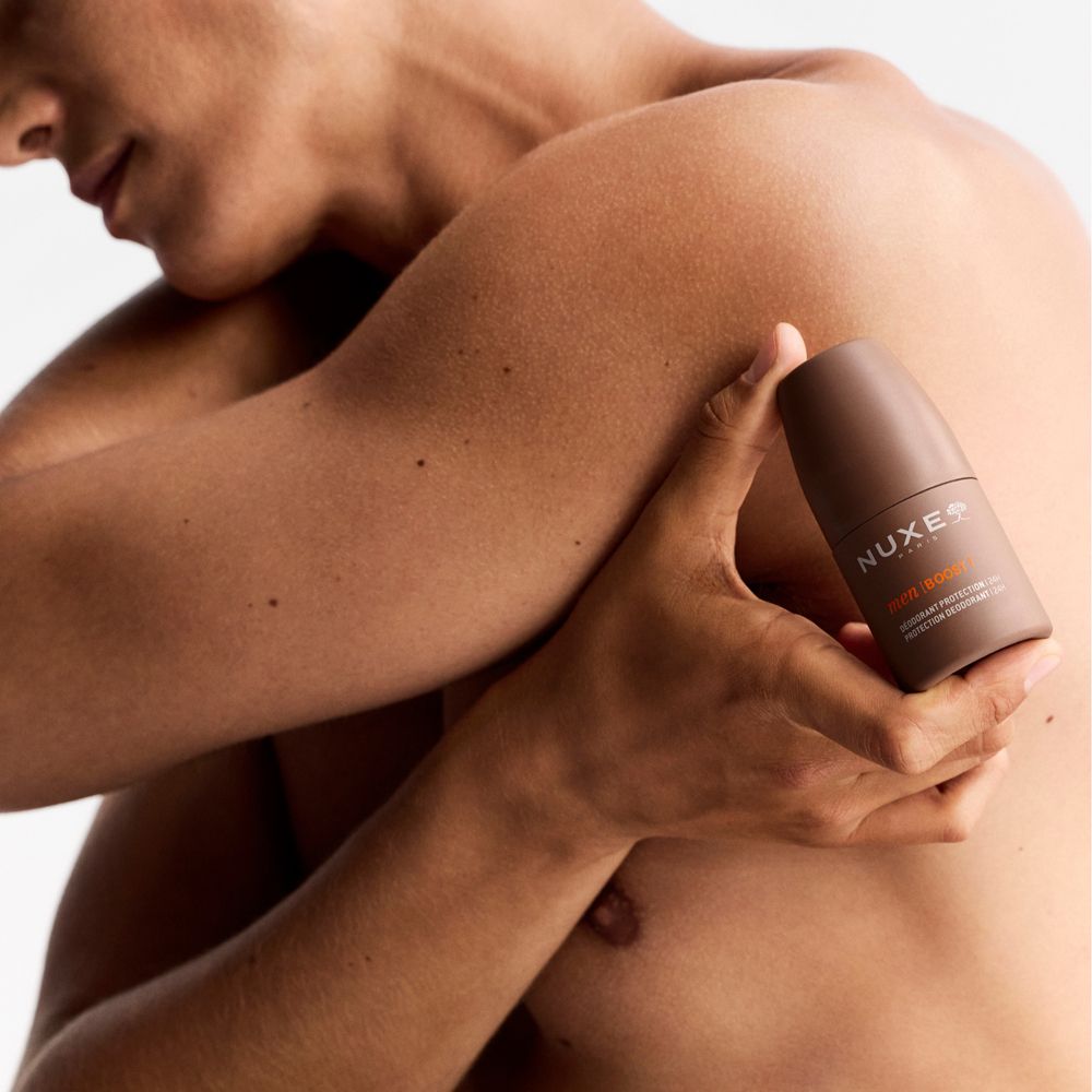 Uomo tiene roll-on deodorante marrone. Visibile: Nuxe Paris, men | BOOST. Senza camicia.