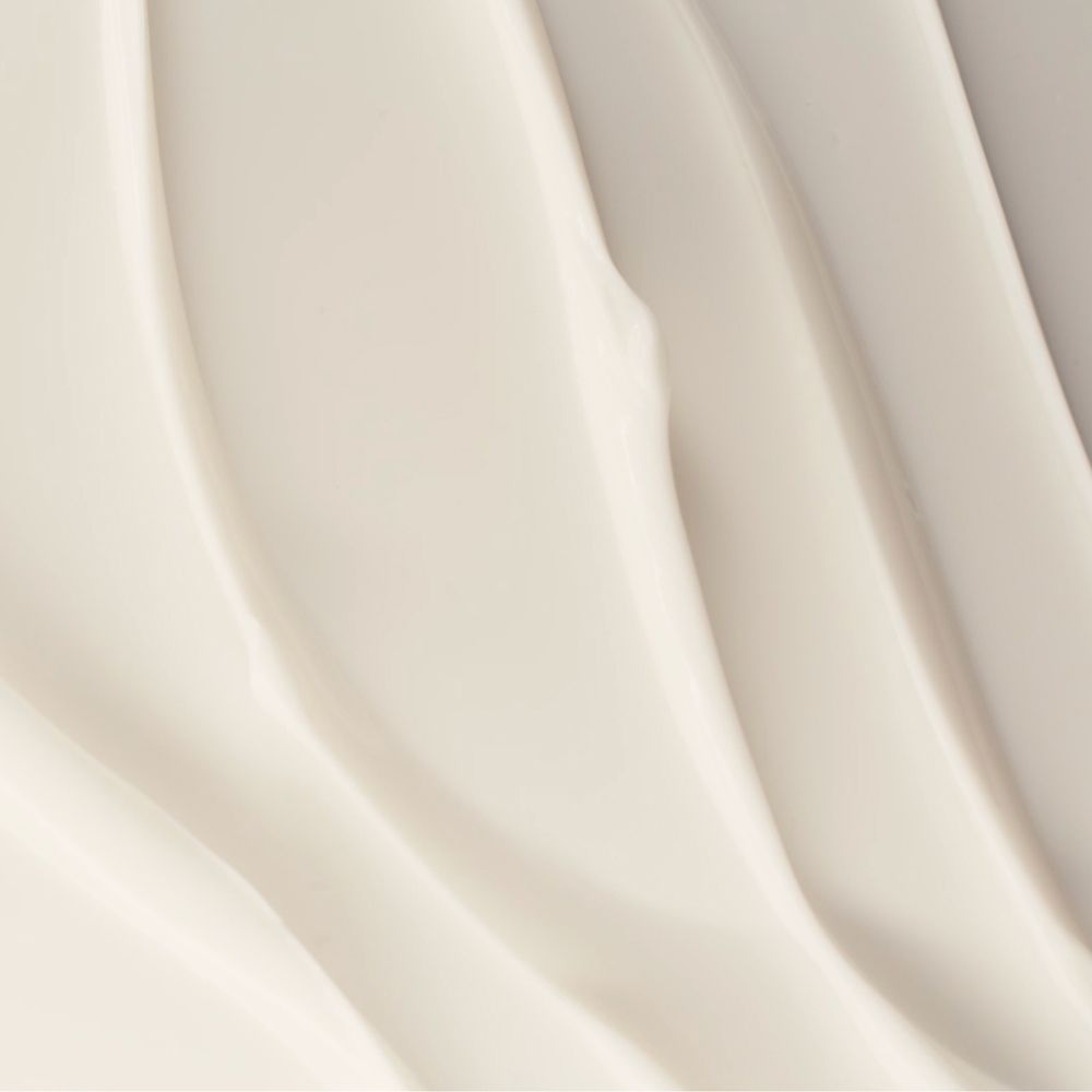 Primo piano di strisce di crema bianca. Texture della crema con linee ondulate. Sfondo grigio chiaro.