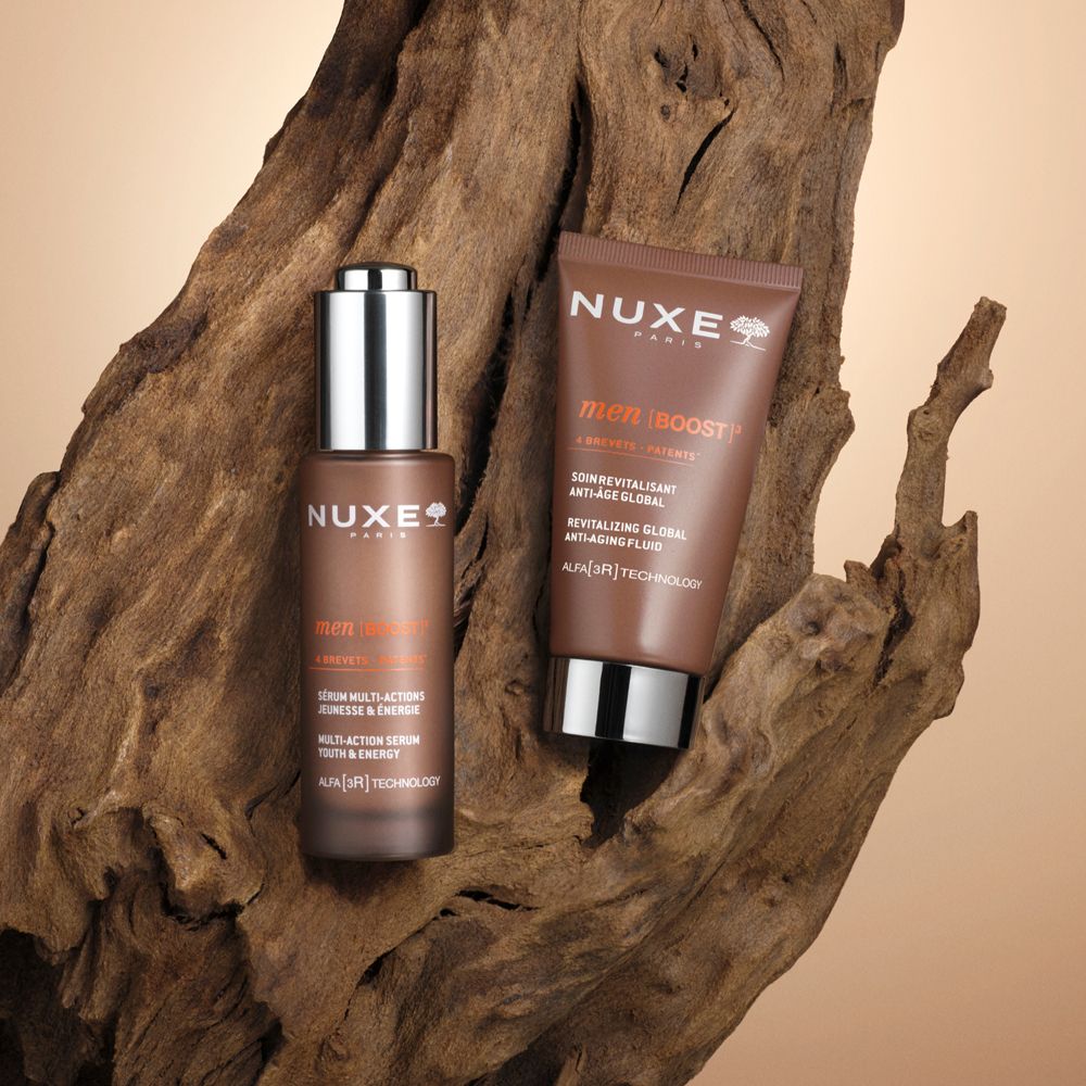 Set di prodotti: flacone e tubo su legno. Scritta: Nuxe Paris, Men Boost, Revitalizing Global Anti-Age Fluid.