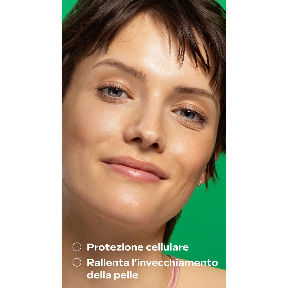 Primo piano di un viso. Pelle con siero. Testo: Protezione cellulare, rallenta l'invecchiamento cutaneo. Sfondo verde.