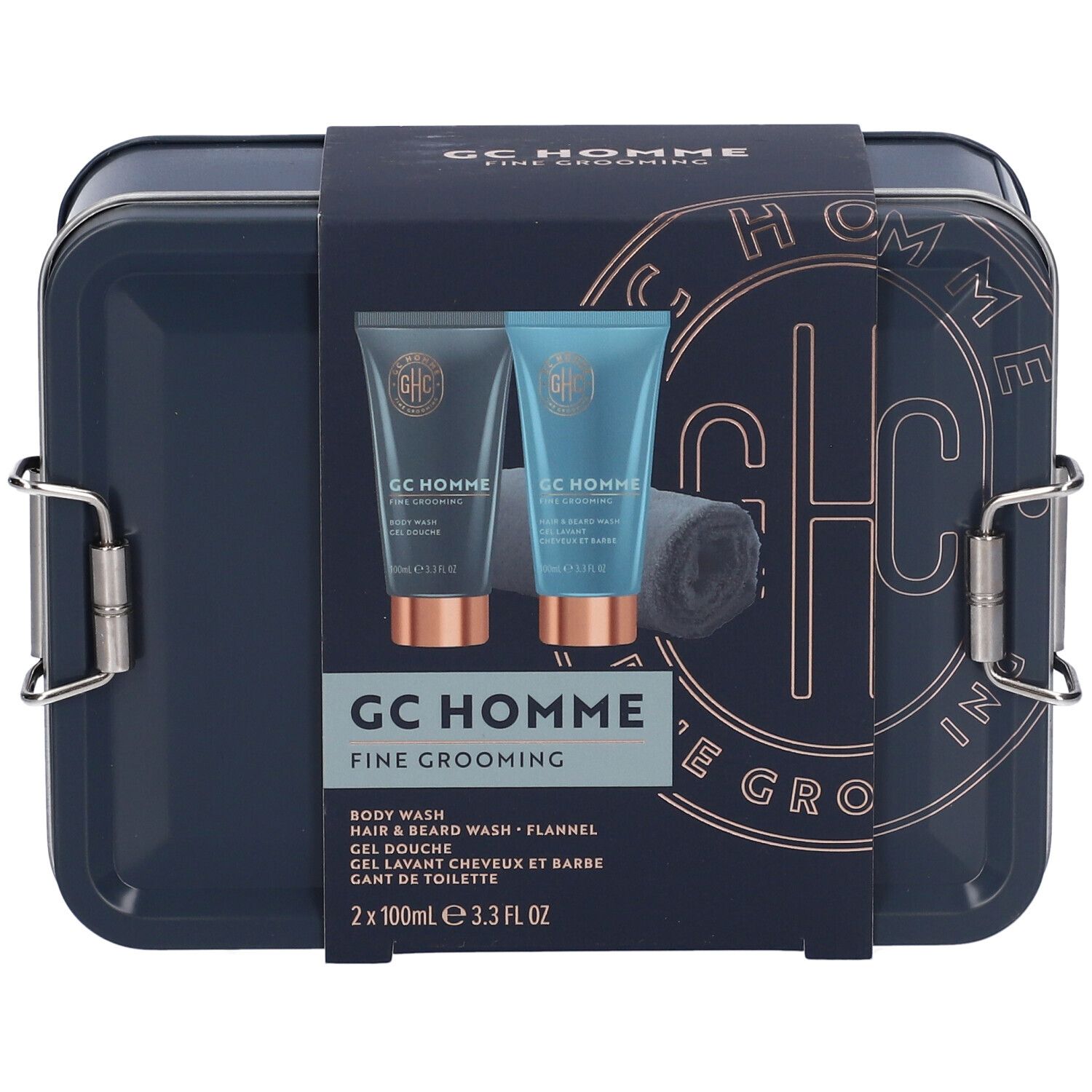 Scatola metallica blu scuro con due tubi e asciugamano. Scritta: GC Homme Fine Grooming.