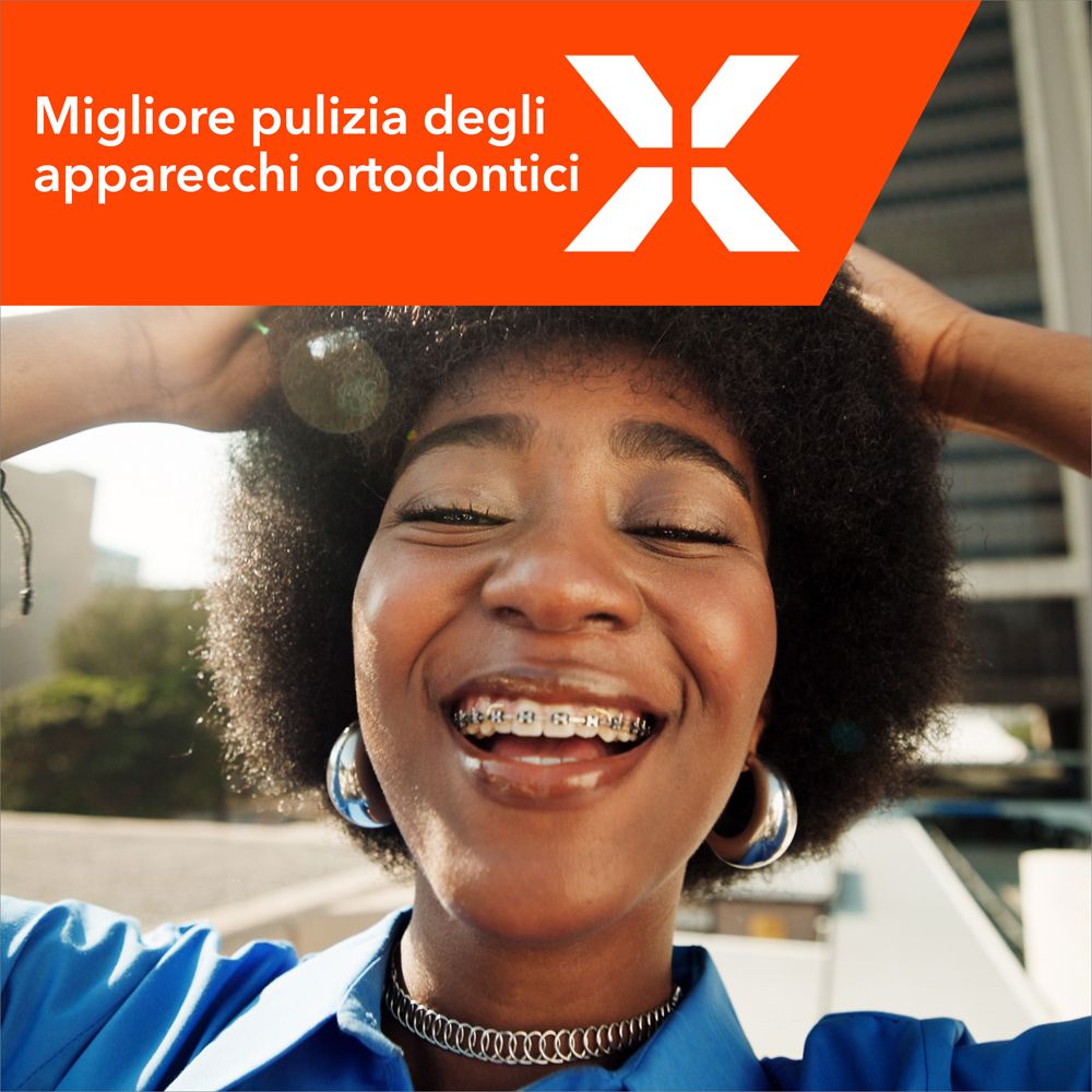 Donna con apparecchio che sorride. Logo Elmex e testo: Migliore pulizia degli apparecchi ortodontici.