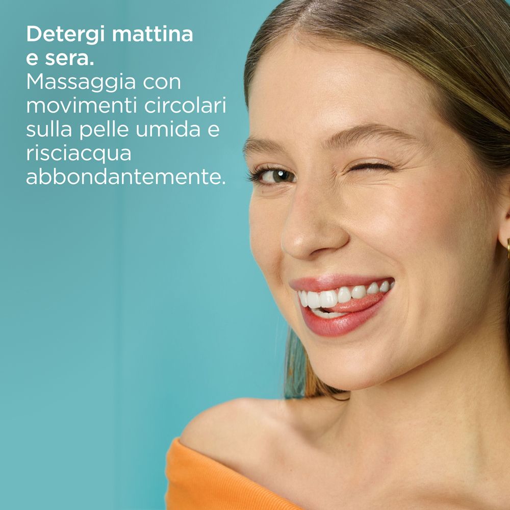 Donna che strizza l'occhio. Testo: Detergere mattina e sera. Massaggiare con movimenti circolari sulla pelle umida.