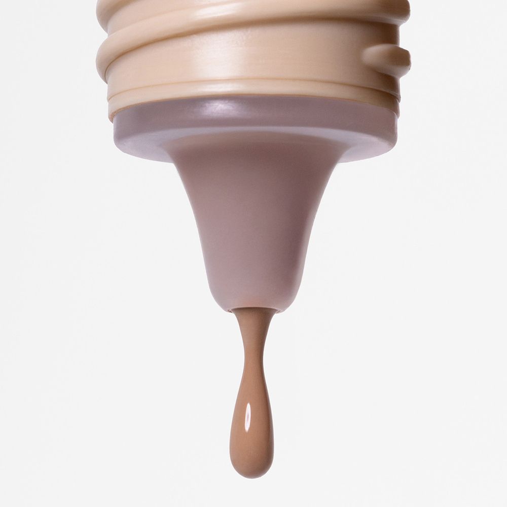 Primo piano di una goccia di fondotinta. Goccia di tonalità della pelle. Apertura del flacone con filettatura beige.