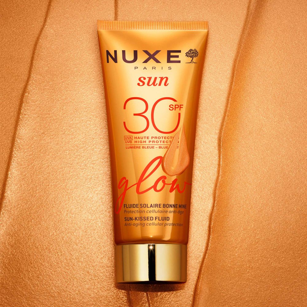 Tubo arancione Nuxe Sun, SPF 30, Glow su tessuto dorato. Tappo dorato. Prodotto viso.