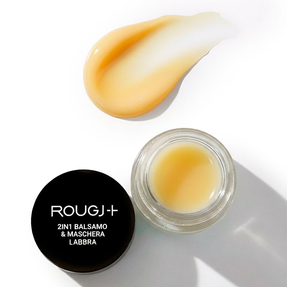 Vasetto aperto con balsamo giallo e traccia di balsamo accanto. Coperchio nero con scritta bianca.