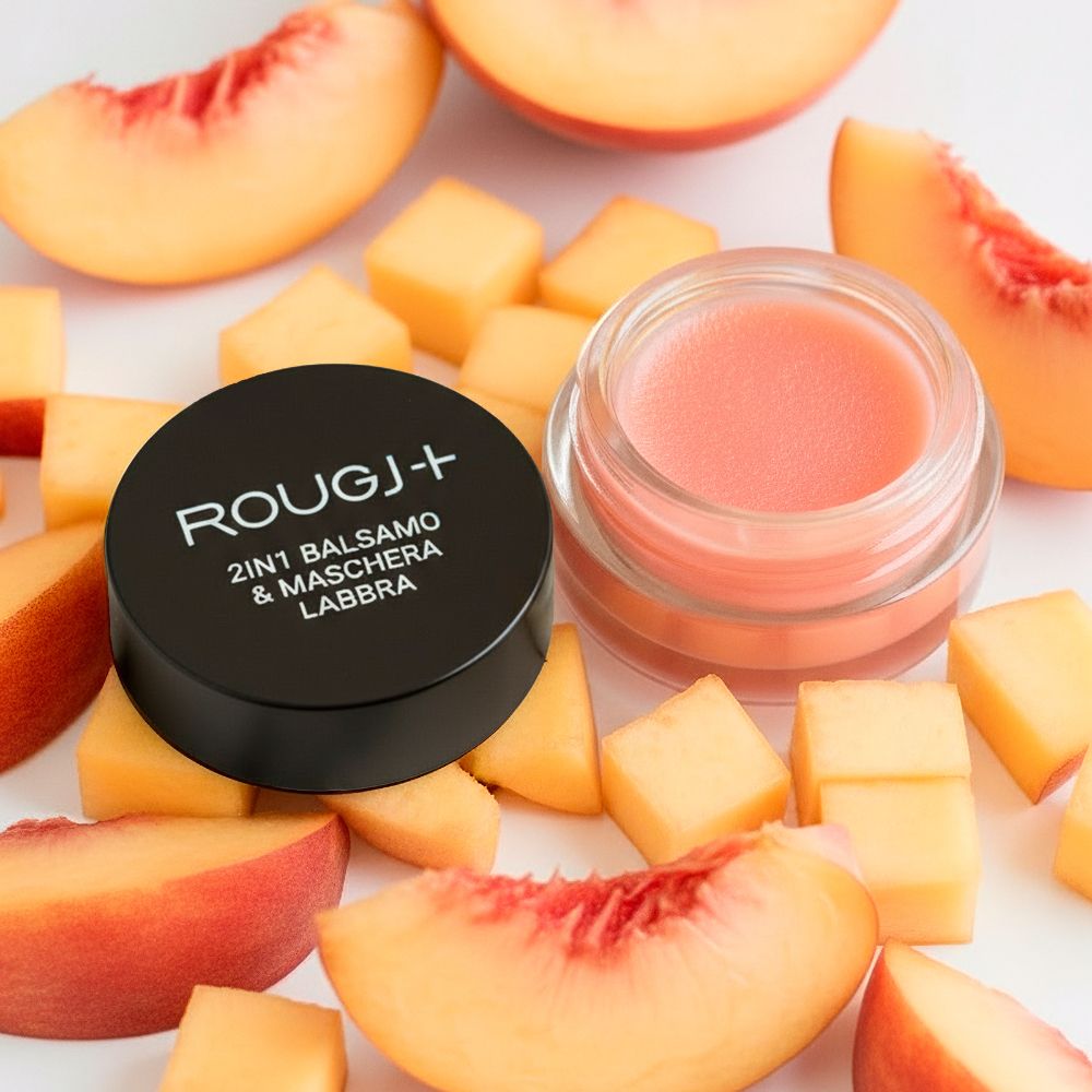 Vasetto di balsamo rosa, coperchio nero con testo. Pezzi di pesca intorno.