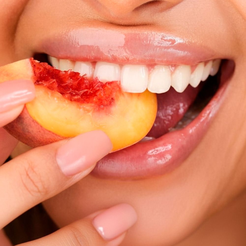 Bocca con labbra lucide. Persona che mangia una fetta di pesca.