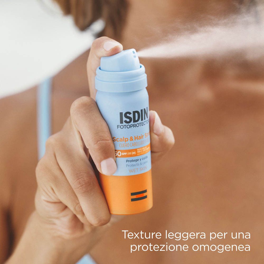 Donna che spruzza Isdin Scalp & Hair Spray SPF50 su cuoio capelluto e capelli.