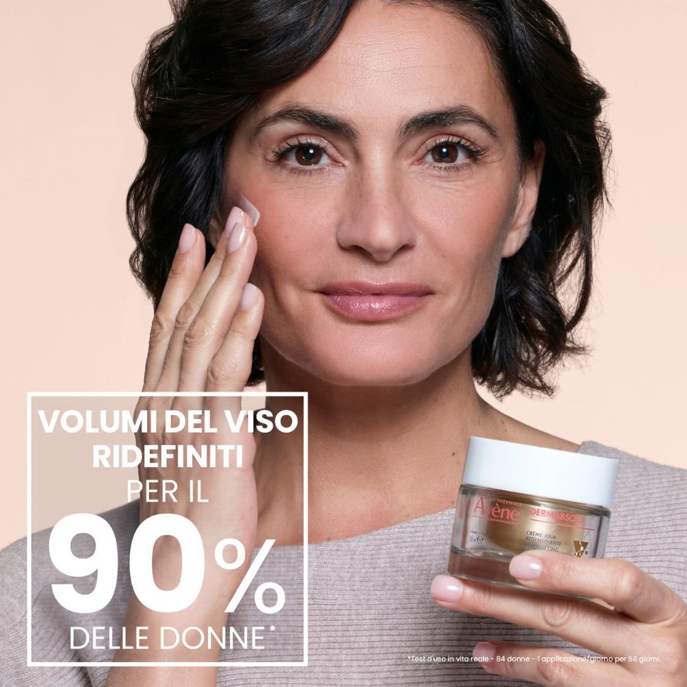 Una donna applica la crema giorno Avène Dermabsolu. Testo e percentuale.