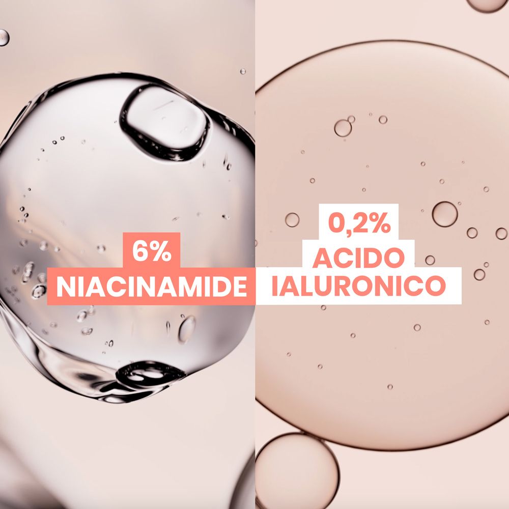 Primo piano di gocce di liquido. Testo: 6% Niacinamid, 0,2% Acido Ialuronico.