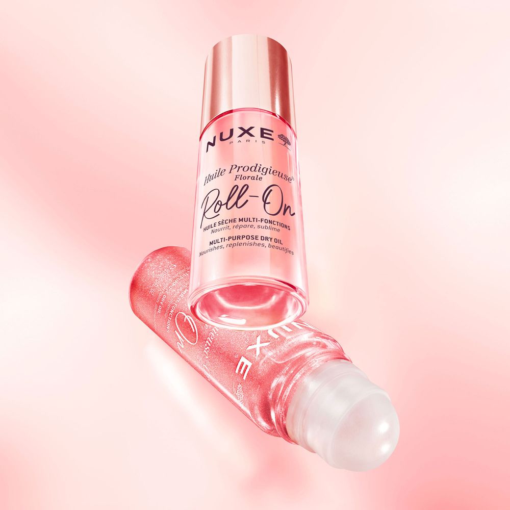 Due Nuxe Huile Prodigieuse Florale Roll-On. Sfondo rosa. Un Roll-On è sdraiato.