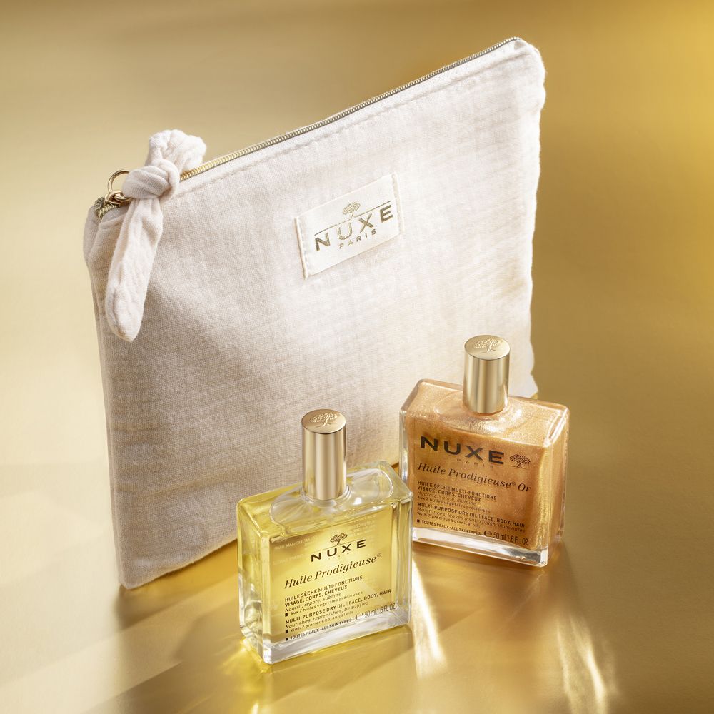 Due flaconi d'olio e una pochette su sfondo dorato. Scritte "Huile Prodigieuse" e "Huile Prodigieuse Or".