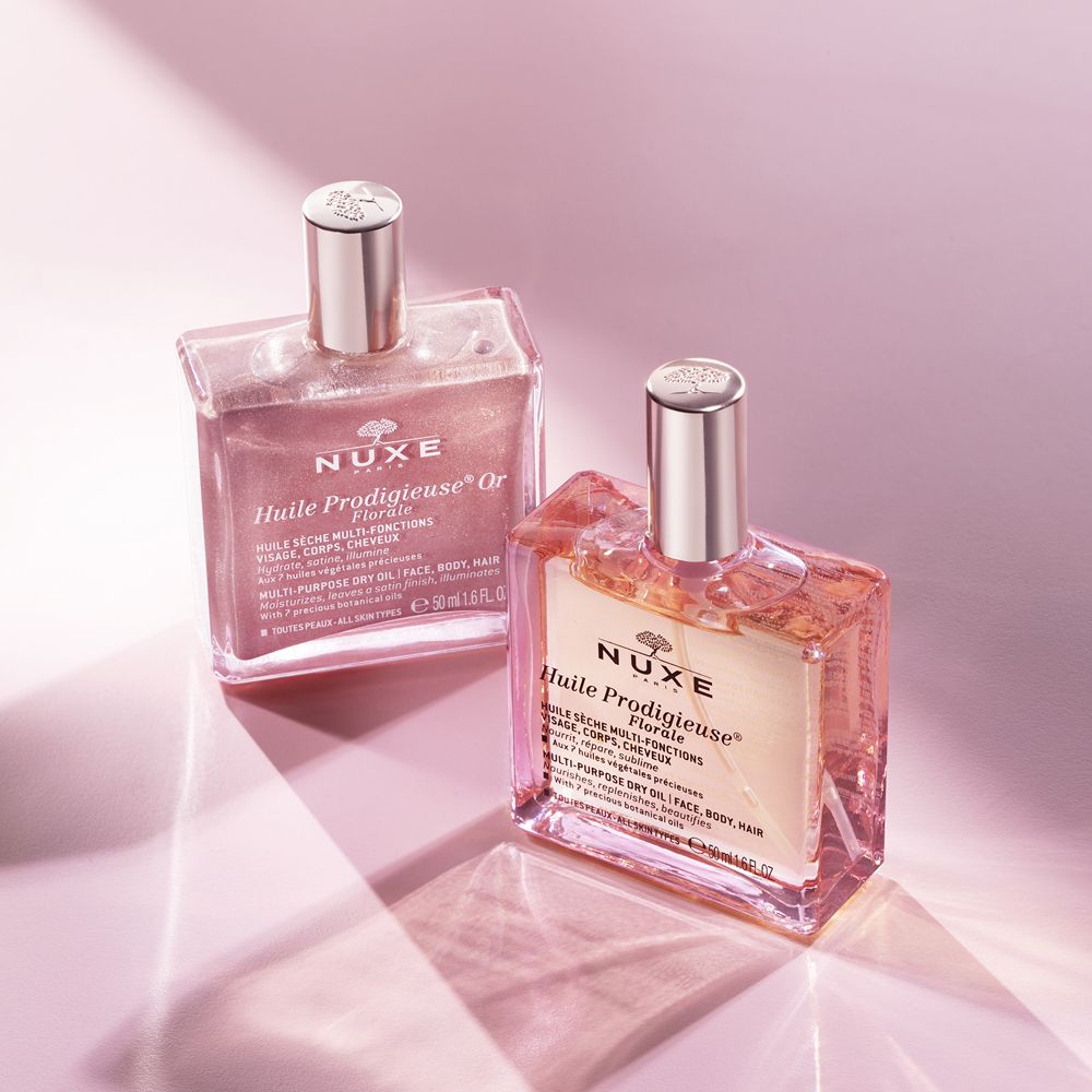 Due flaconi con liquido rosa e dorato. Scritta: Nuxe. Flaconi con vaporizzatore.