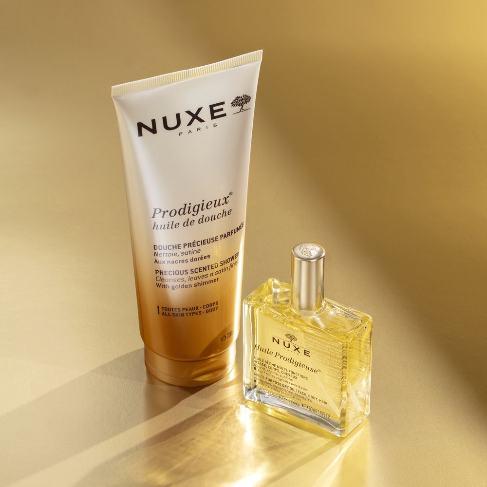 Gel doccia e olio Nuxe. Entrambi i prodotti hanno confezioni dorate. Logo Nuxe e nomi dei prodotti visibili.