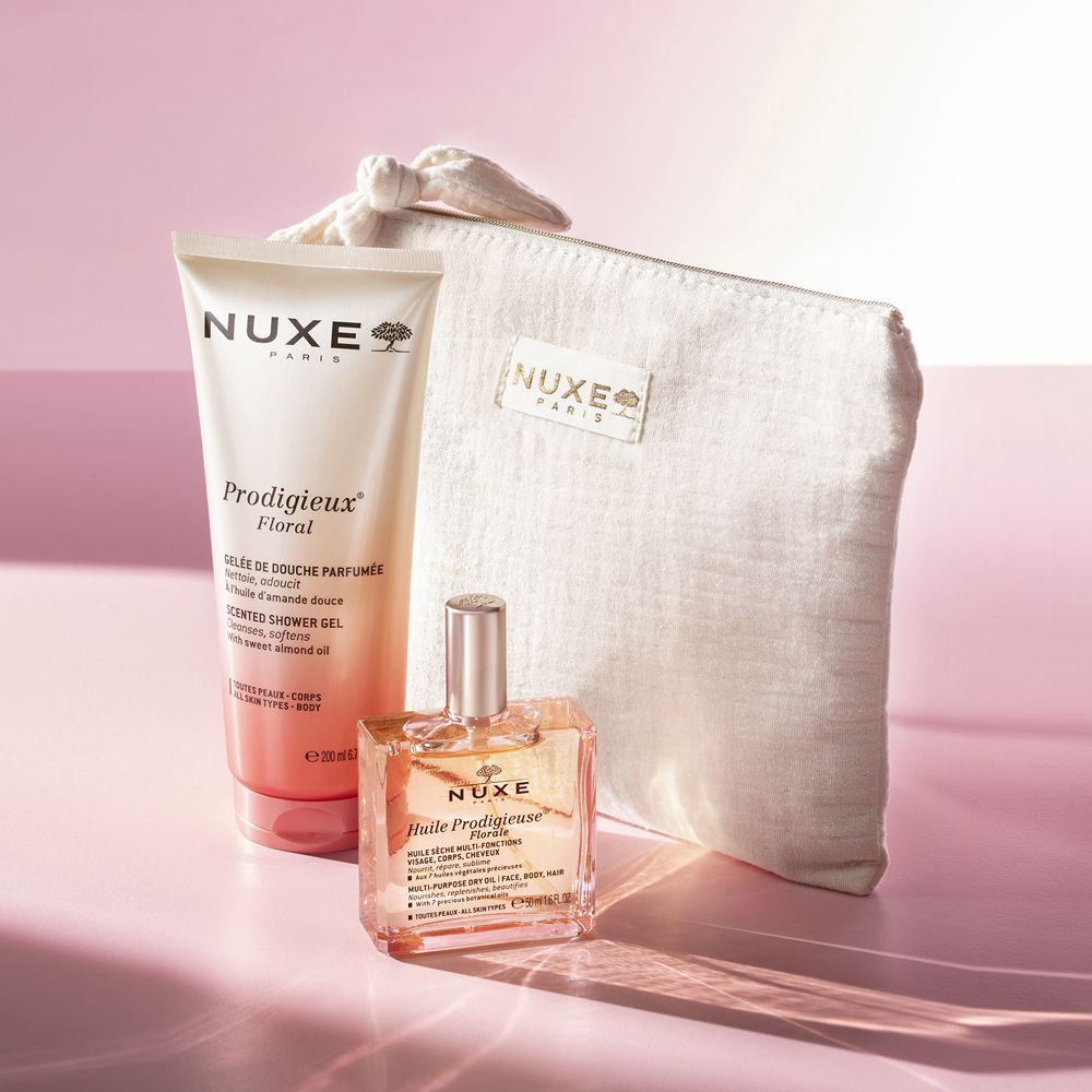 Set regalo con gel doccia, olio e pochette. Prodotti su sfondo rosa. Testo: Nuxe, Prodigieux Floral. Pochette con logo.