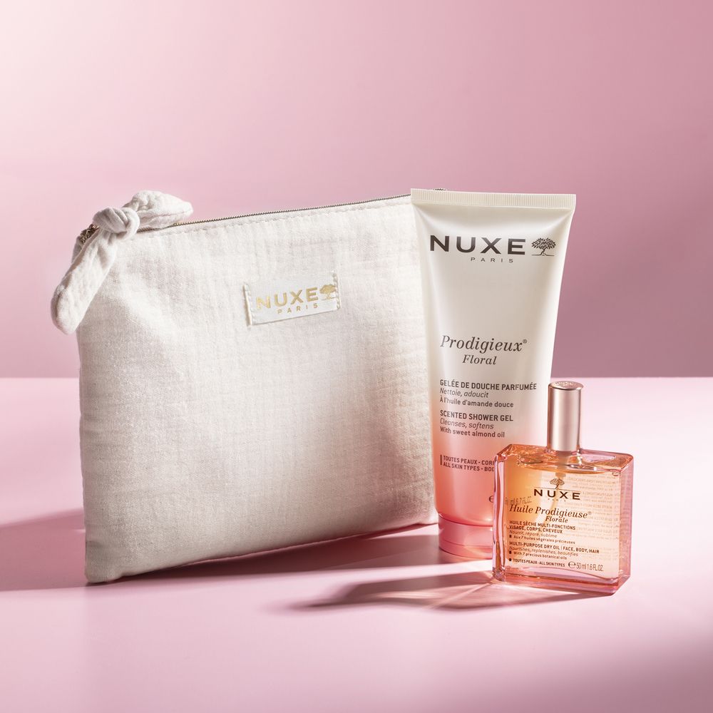 Set regalo con gel doccia, olio e pochette. Prodotti su sfondo rosa. Testo: Nuxe, Prodigieux Floral. Pochette con logo.