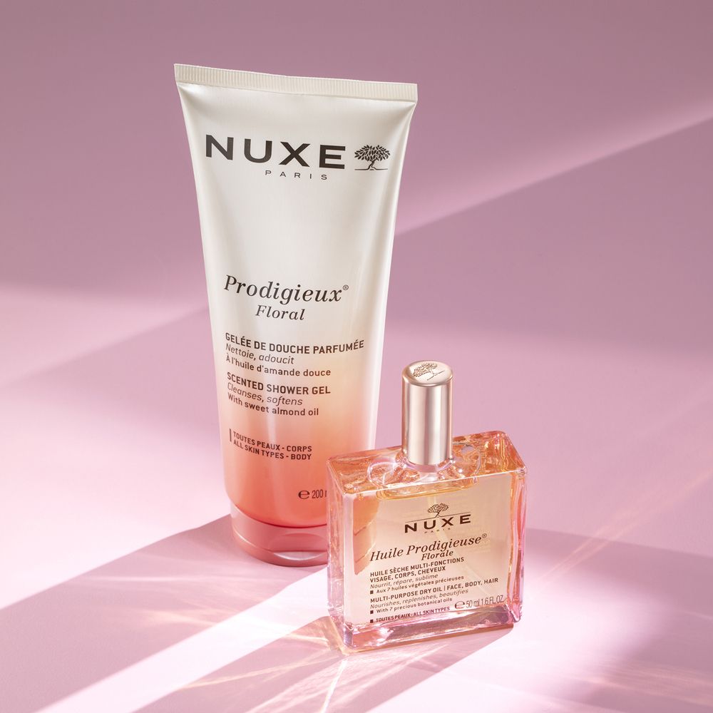 Gel doccia e olio su sfondo rosa. Testo: Nuxe, Prodigieux Floral. Flacone e tubo. Effetto ombra.