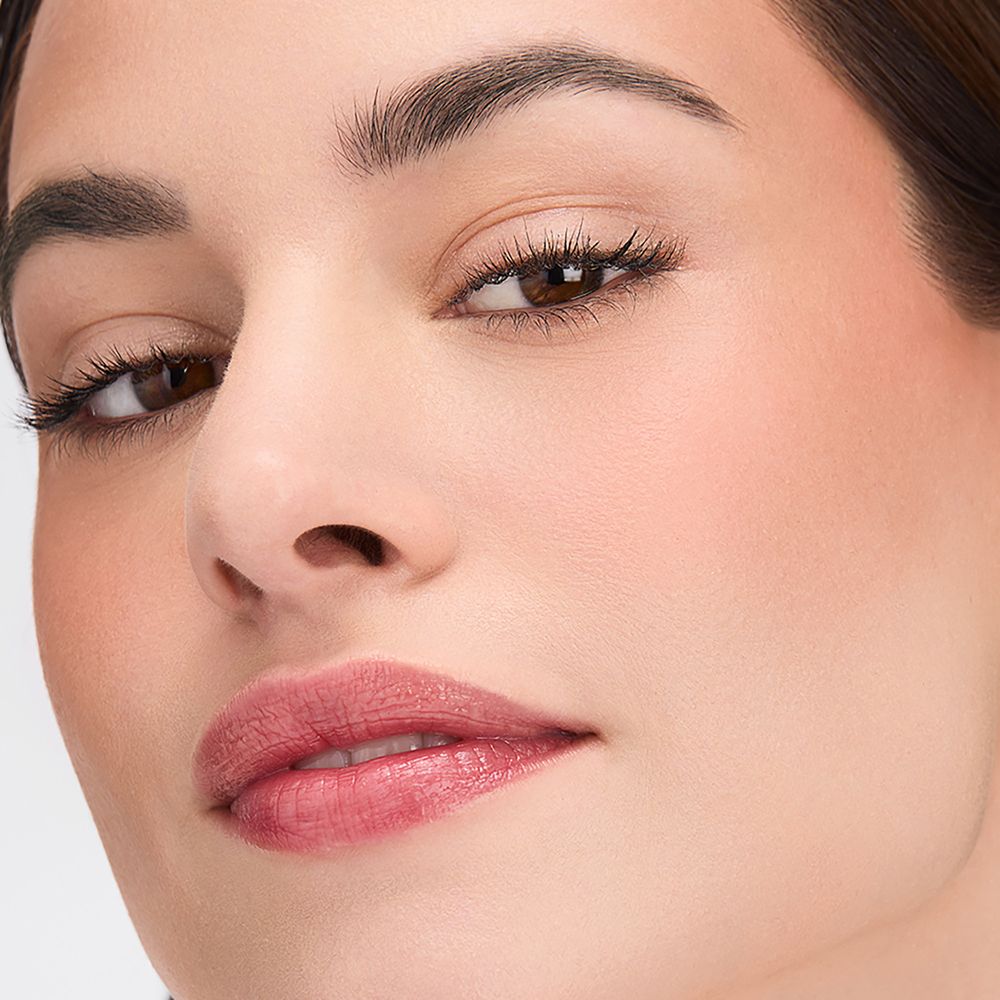 Primo piano di un viso. Pelle abbronzata, rossetto. Sopracciglia e ciglia evidenziate.