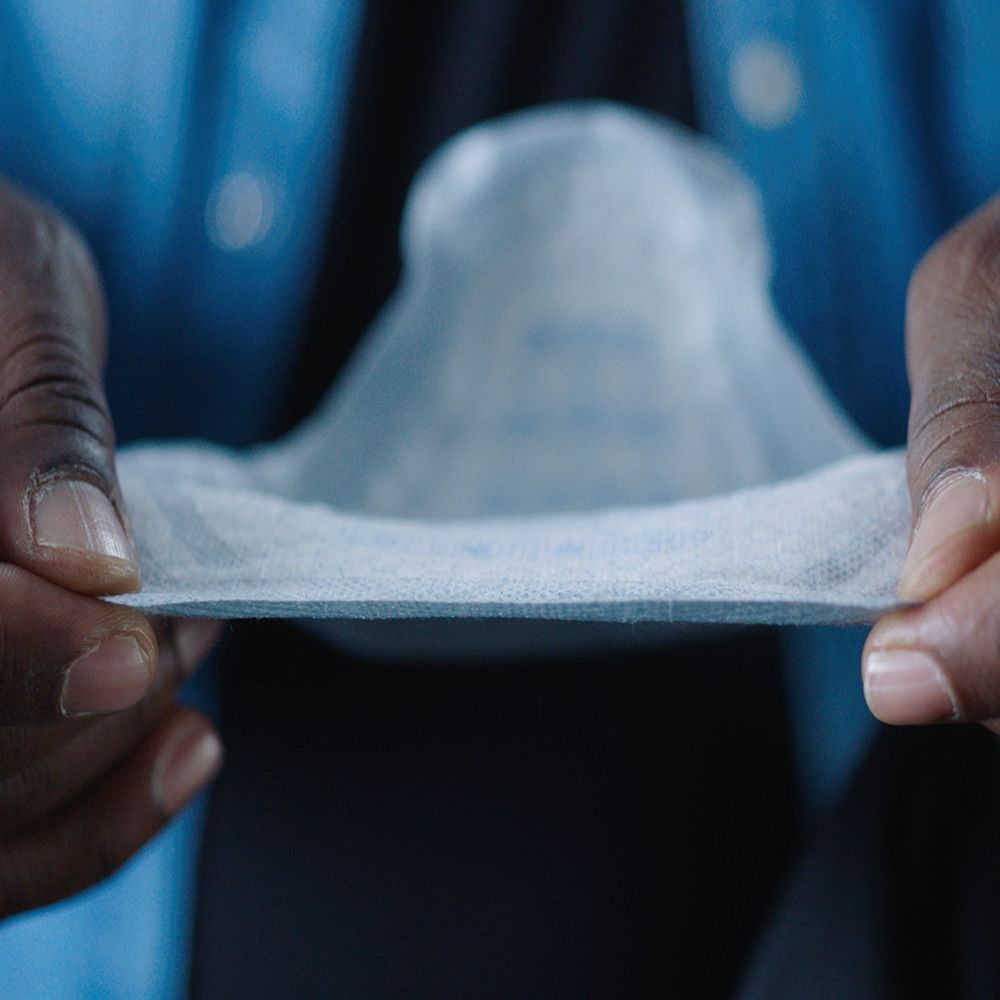 Protezione per incontinenza tenuta in mano. Bianco e blu. Texture visibile.