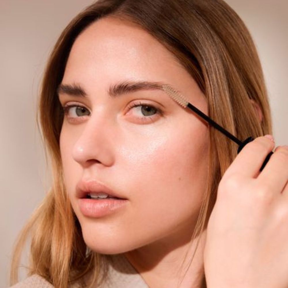 Donna con gel per sopracciglia. Spazzola nera applicata alle sopracciglia. Pelle chiara, capelli castani.