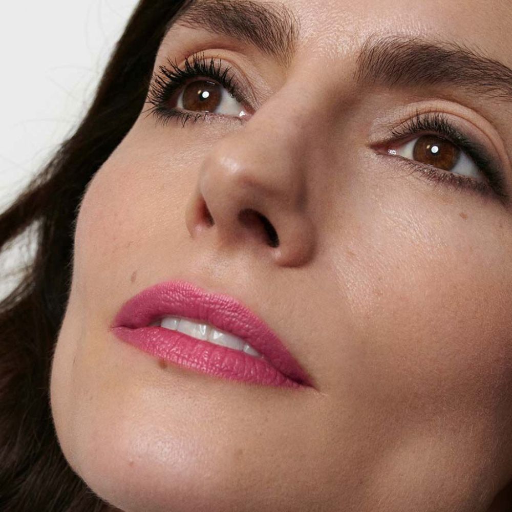 Primo piano di un viso con labbra rosa. La persona guarda in alto.