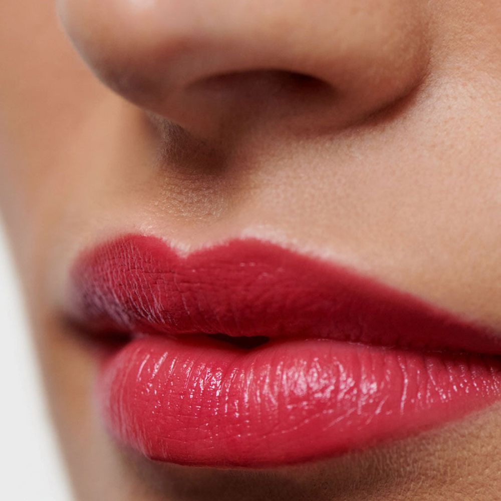 Primo piano di labbra con rossetto rosa-rosso. Labbra leggermente socchiuse.