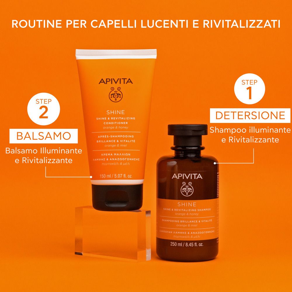 Due flaconi su sfondo arancione. Un tubo e una bottiglia con scritta: APIVITA SHINE. Testo: Routine per capelli lucenti e rivitalizzati.