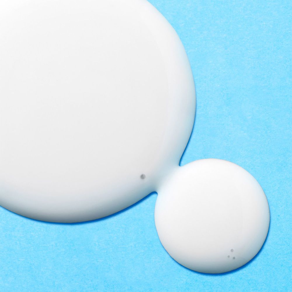 Due gocce di siero bianco su sfondo azzurro. Piccoli punti.