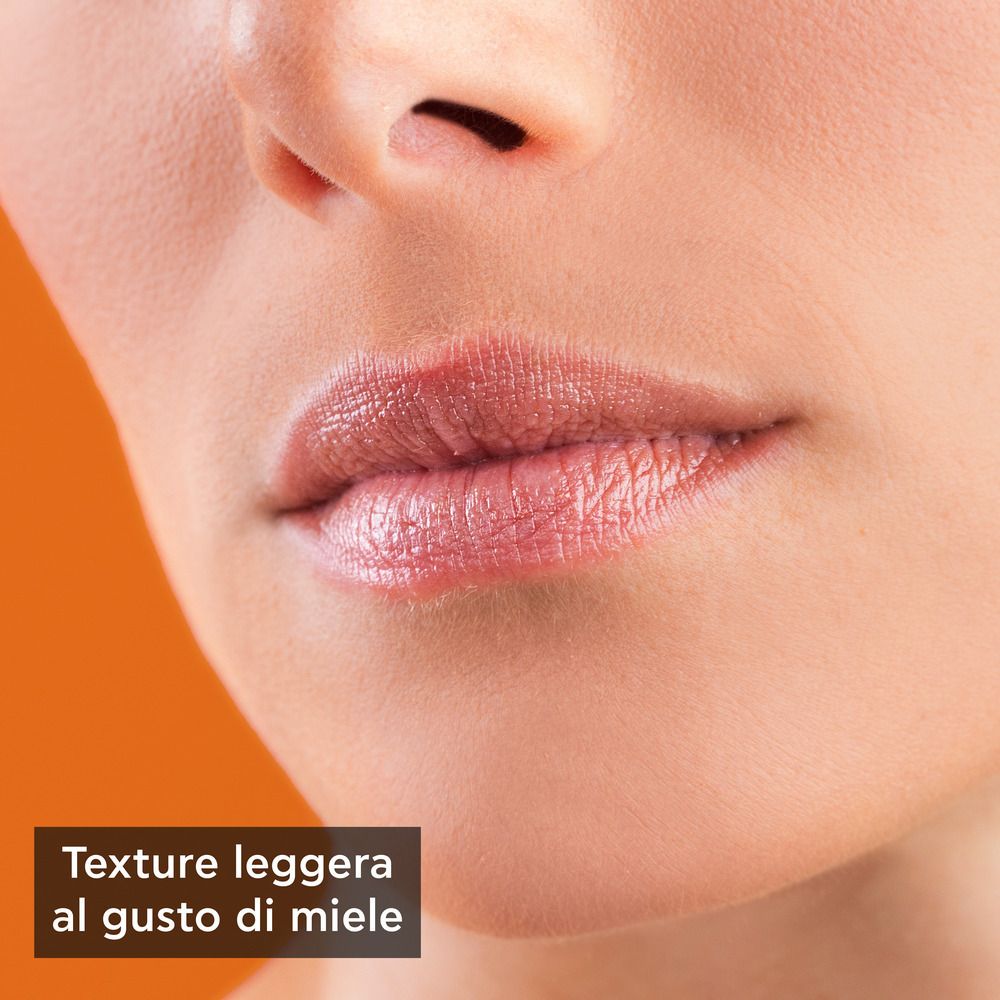 Primo piano delle labbra. Rossetto applicato. Testo: Texture leggera al gusto di miele.