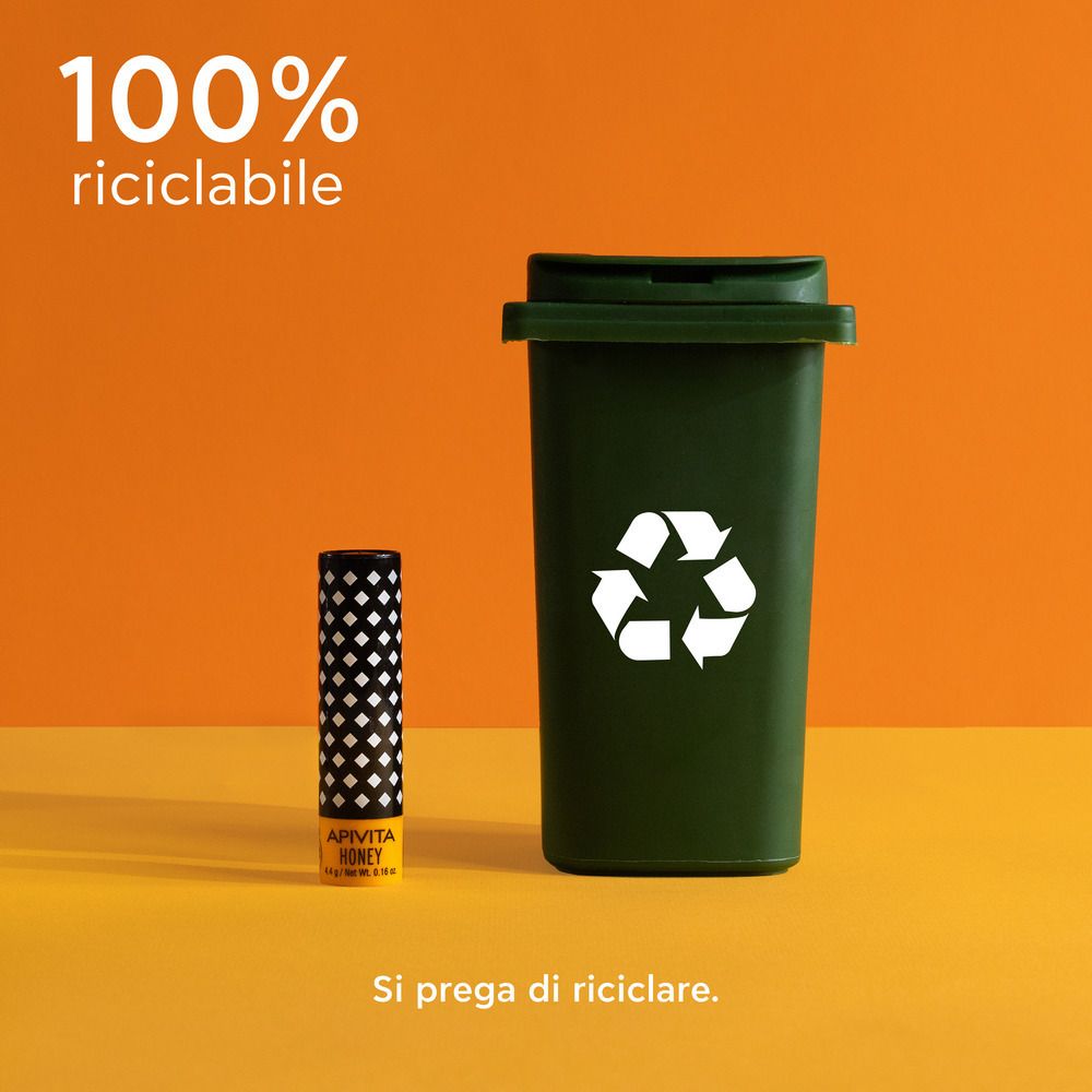 Balsamo labbra accanto a un bidone della spazzatura verde. Sfondo arancione. Testo: 100% riciclabile.