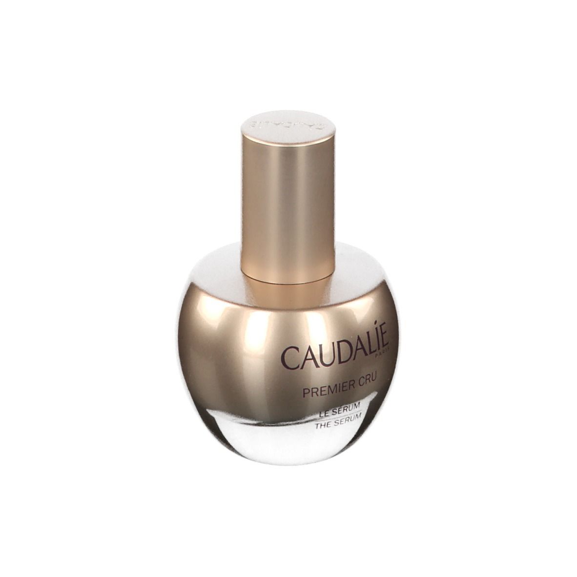 Flacone di siero. Flacone dorato con scritta CAUDALIE Premier Cru. Sfondo bianco.