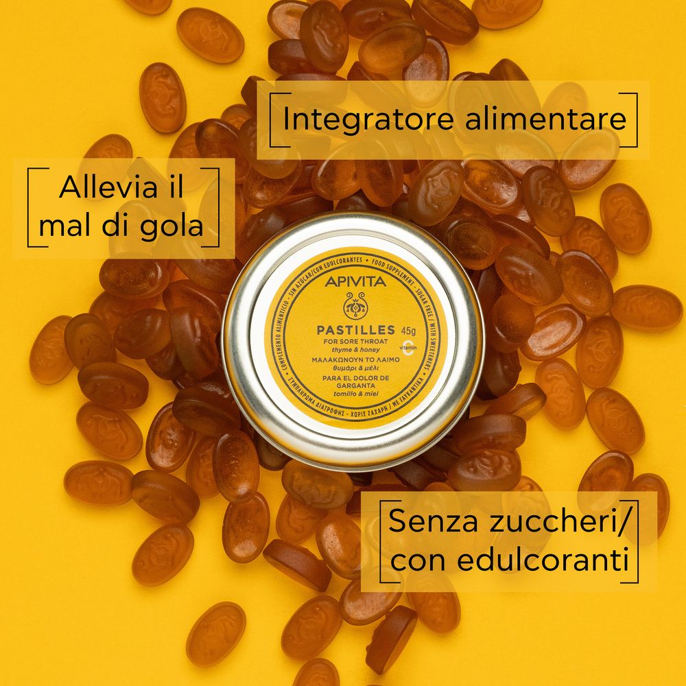 Pastiglie gialle intorno a un barattolo. Testo: Integratore alimentare, Alleva il mal di gola, Senza zuccheri.