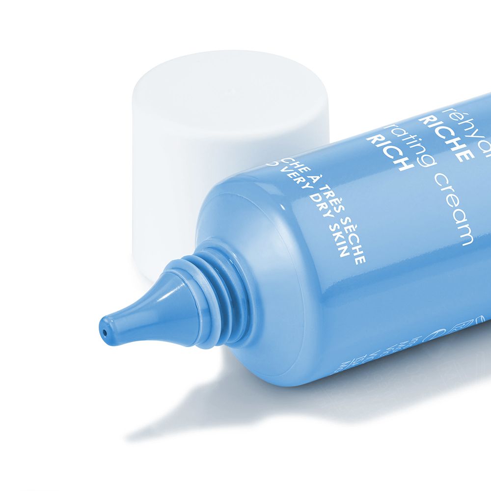 Primo piano di un tubo blu con tappo bianco. Testo: Crème réhydratante Riche. Beccuccio del tubo visibile.